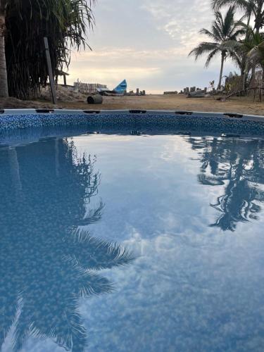 a swimming pool next to a beach with palm trees at tierrabrava-hospedaje in Cojimíes