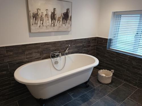 a bath tub in a bathroom with a painting on the wall at The Stables at Eriviat Hall in Henllan