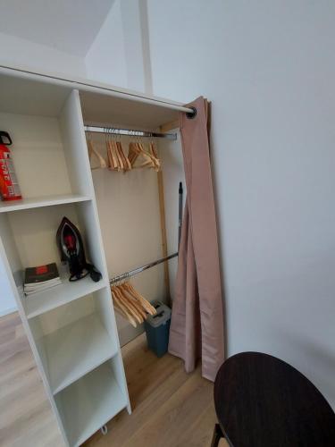 een kamer met een kast met witte planken bij Studio confort #2, proche Gare et commodités in Maubeuge