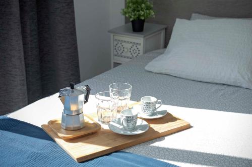 een dienblad met een koffiezetapparaat en glazen op een bed bij Sur Restinga in La Restinga