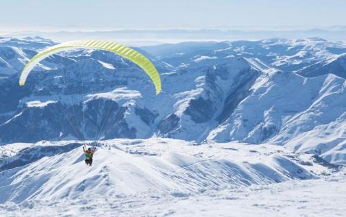 a person flying a parachute on top of a mountain at Delux apartment next to ice rink in Gudauri