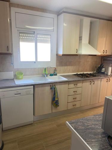 a kitchen with white cabinets and a sink and a window at Casa con Gran Piscina particular cerca playa in Torredembarra