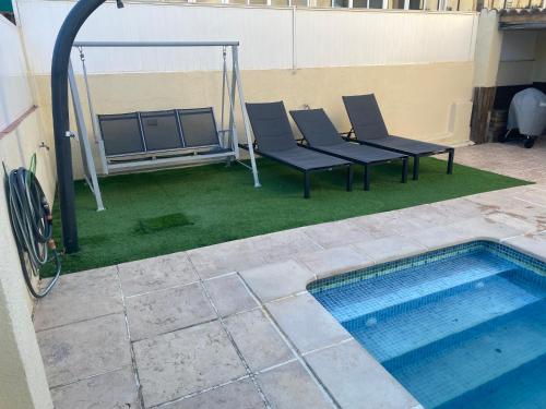 a patio with chairs and a swimming pool at Casa con Gran Piscina particular cerca playa in Torredembarra