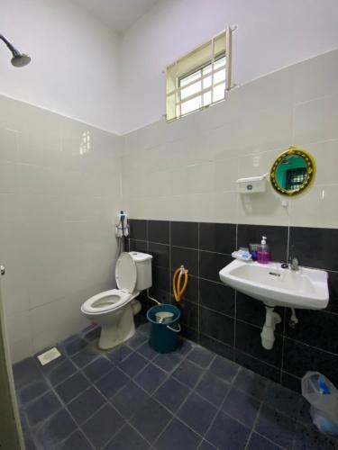een badkamer met een toilet, een wastafel en een spiegel bij DeSyafiq Homestay in Kuala Kedah