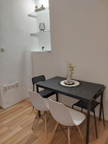 einem schwarzen Tisch mit weißen Stühlen und einer Vase darauf in der Unterkunft Creative studio 4 in Novi Sad