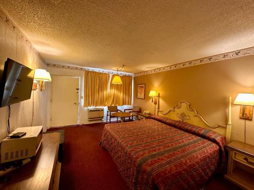 een hotelkamer met een bed en een televisie bij Ambassy Motel in Salina