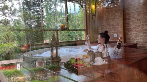 a woman sitting in a bath tub with a window at Pousada Bucaneve in Monte Verde