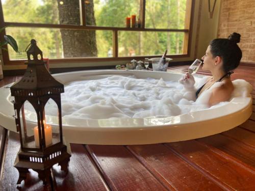 a woman is sitting in a bath tub with a candle at Pousada Bucaneve in Monte Verde
