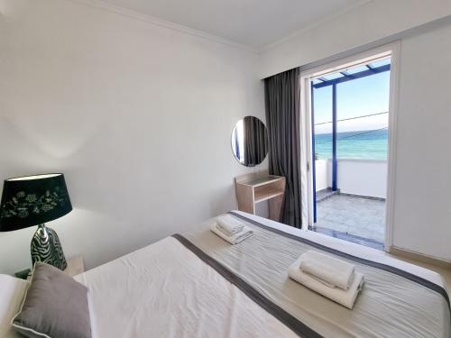 a bedroom with a bed with a view of the ocean at Chios Xenia Studios & Apartments in Paralia Agias Foteinis