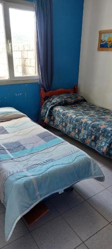 two beds in a room with a window at Habitación en casa in San Carlos de Bariloche