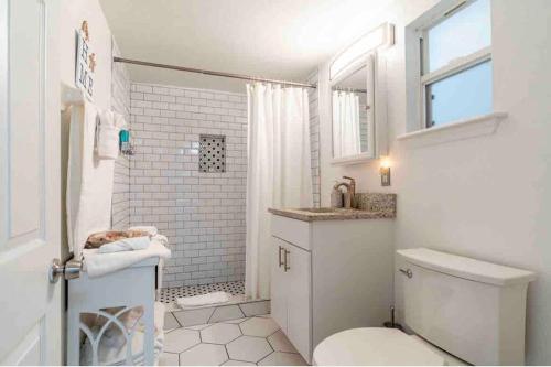 y baño blanco con aseo y ducha. en Lovely 2 bedrooms, steps away from the beach., en Bradenton Beach