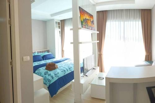 a bedroom with a bed and a desk and a window at Fluffy bed and seaview @Bangsaen in Bangsaen