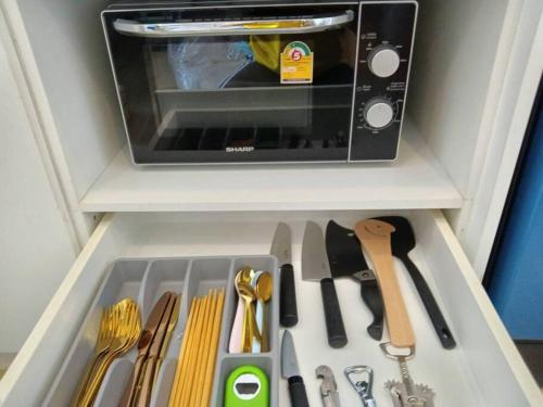 a drawer filled with kitchen utensils and a microwave at Fluffy bed and seaview @Bangsaen in Bangsaen
