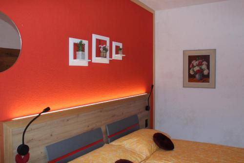 a bedroom with a bed with an orange wall at Hotel Urirotstock in Isenthal