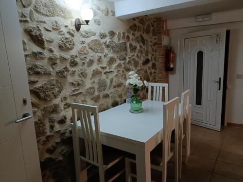 una mesa y sillas en una habitación con una pared de piedra en Casa Rural Roquemar, en Guijo de Granadilla