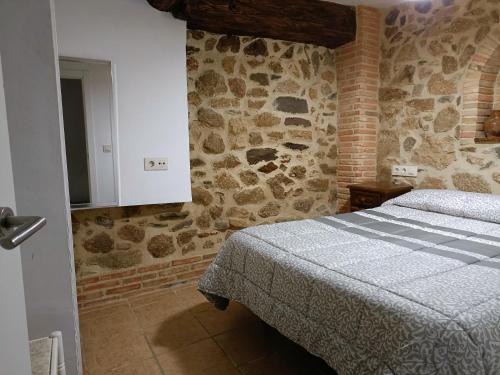a bedroom with a bed and a stone wall at Apartamento o Casa Rural Roquemar in Guijo de Granadilla