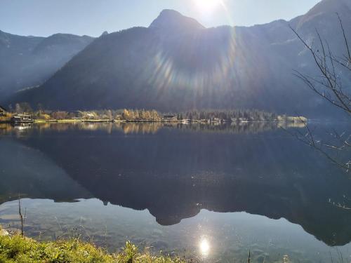 a view of a lake with the sun reflecting on the water at Seehof Royer in Obertraun