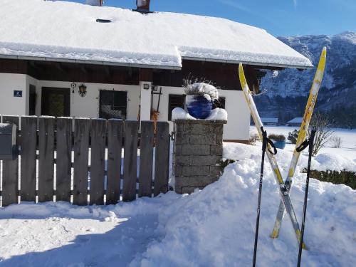 a house covered in snow with skis in front of it at Seehof Royer in Obertraun