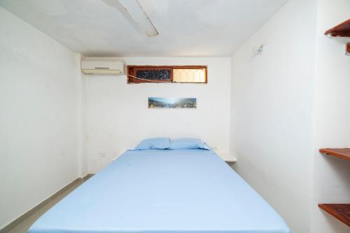 a small bedroom with a bed in a white room at ApartaHostal Mafelo in Taganga