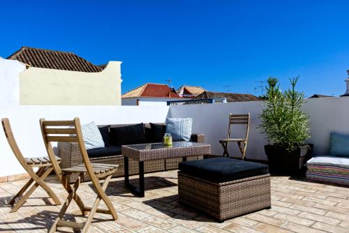 a patio with chairs and a couch on a roof at Casa Valerie - Etramures in Tavira