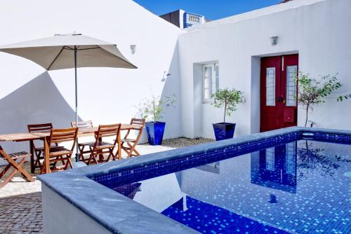 a house with a swimming pool and a table with an umbrella at Casa Valerie - Etramures in Tavira