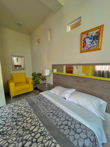 - une chambre avec un grand lit et une chaise jaune dans l'établissement OYO Hotel Museo Carnaval, à Huejotzingo