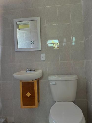 La salle de bains est pourvue de toilettes, d'un lavabo et d'un miroir. dans l'établissement OYO Hotel Museo Carnaval, à Huejotzingo