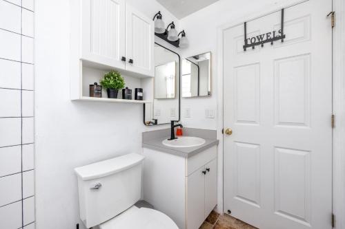 a white bathroom with a toilet and a sink at Blue Heron Lakeview Pool Home Close to Clearwater in Largo