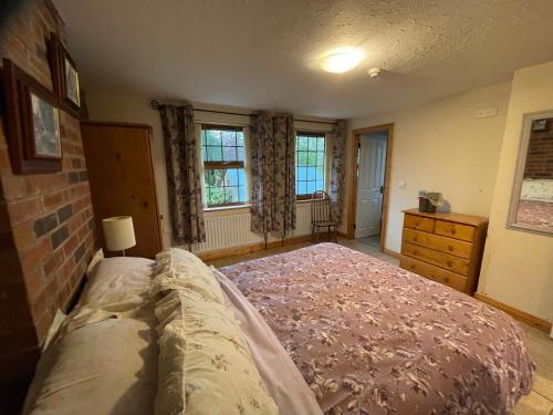 um quarto com uma cama, uma cómoda e janelas em The Slates Apartments - Fuchsia & Orchard Apartments em Irvinestown