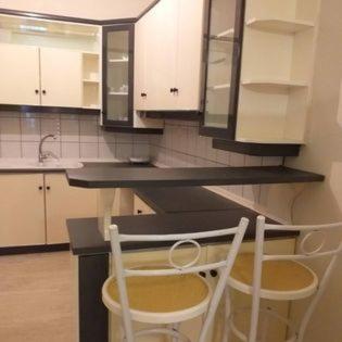 a kitchen with white cabinets and two white chairs at MARIOS HOUSE 1 in Xanthi