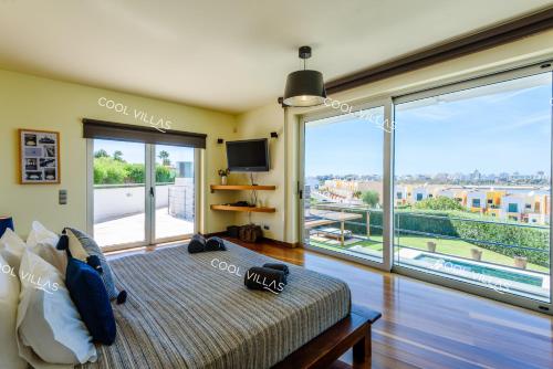 a bedroom with a bed and a large window at Ferragudo Premium Villa - heatable pool & river views in Ferragudo