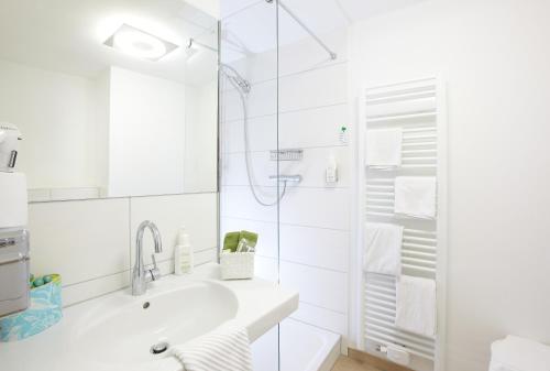 a white bathroom with a sink and a shower at Hotel Klingelhöffer in Alsfeld