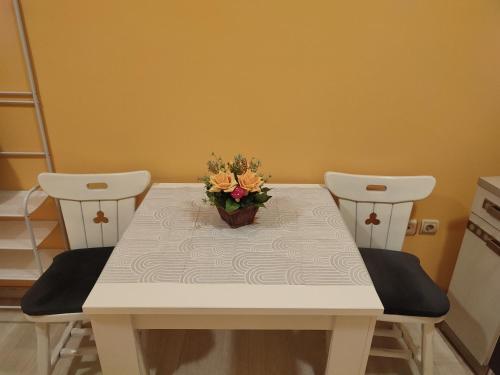 een tafel met twee stoelen en een vaas met bloemen erop bij Apartman Lara in Kruševac