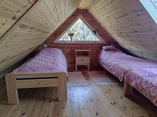 Habitación de madera con 2 camas y ventana en KTA TARPAN Mały Domek, en Masiewo