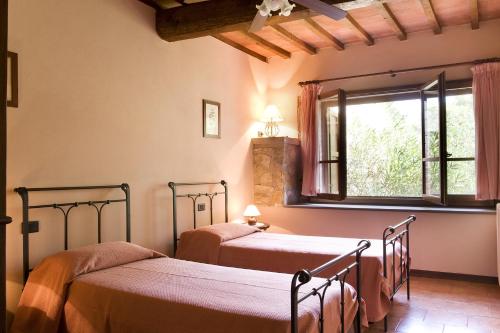 two beds in a room with a window at Poggio Ugo in Bucine