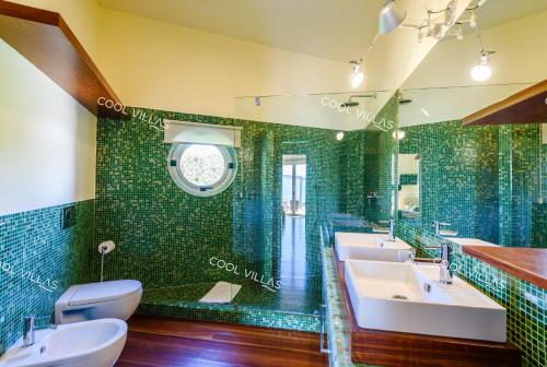 a bathroom with two sinks and a green tiled wall at Ferragudo Premium Villa - heatable pool & river views in Ferragudo
