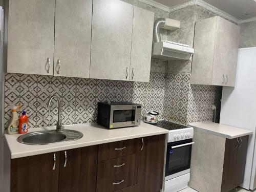 a small kitchen with a sink and a microwave at Студия в ЖК Ушсункар in Almaty