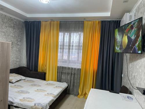 a room with two beds and a window with curtains at Студия в ЖК Ушсункар in Almaty
