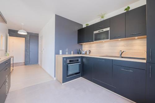 a kitchen with black cabinets and a sink at Sunny Lake by Plaza - Proche Disneyland Paris in Serris