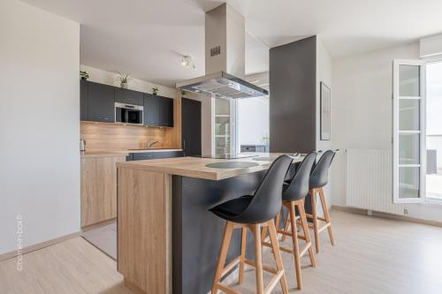 une cuisine avec un îlot et des tabourets de bar dans l'établissement Sunny Lake by Plaza - Proche Disneyland Paris, à Serris