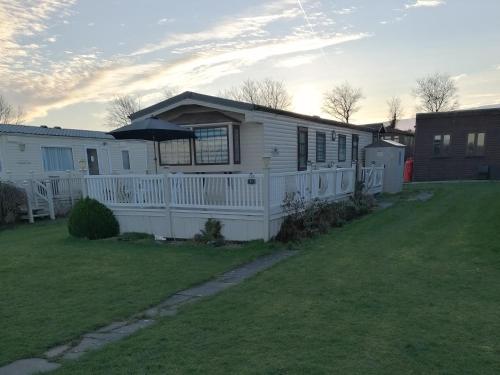 a white house with a fence in a yard at Cornwall CORNWALL-CHAPMANSWELL CARAVAN HOLIDAY PARK A30 B&B Bed and breakfast #41 in Launceston