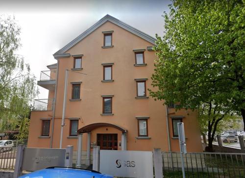 duży pomarańczowy budynek z płotem przed nim w obiekcie Apartments Katrca Bežigrad w Lublanie