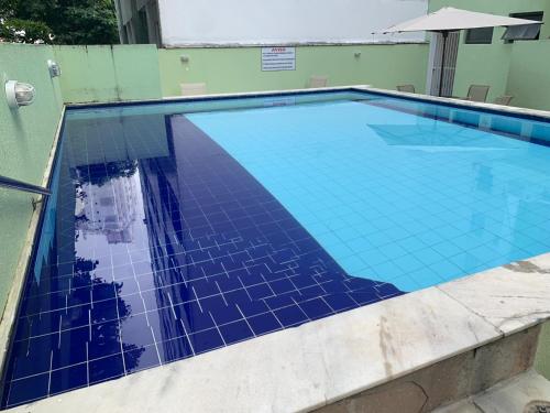 a swimming pool with blue tiles on the top of it at Barra Apart Service in Salvador