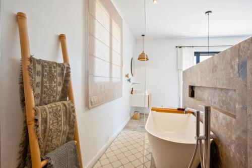 La salle de bains est pourvue d'une baignoire blanche et d'une chaise. dans l'établissement Maison en pierre Corse avec vue proche des Gorges de l'Asco entre mer montagne et piscine, à Moltifao