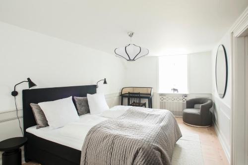 a white bedroom with a bed and a chair at Modern 3BR Duplex Apartment in Nyhavn w Private Balcony in Copenhagen