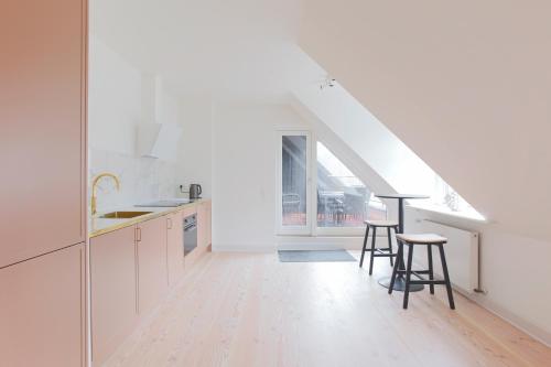 a kitchen with white cabinets and a table and stools at Modern 3BR Duplex Apartment in Nyhavn w Private Balcony in Copenhagen