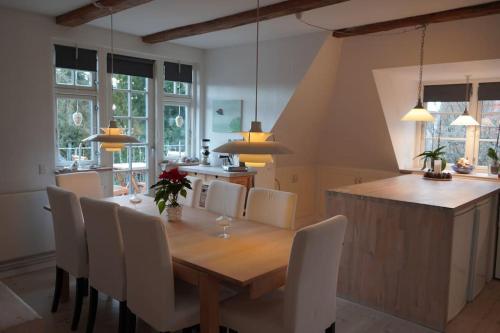 a dining room with a wooden table and white chairs at villa apartment with sea view in Copenhagen