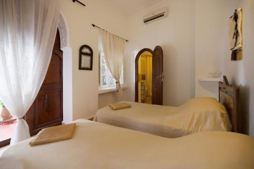 a bedroom with two beds and a window and a door at Riad Noor Charana in Marrakesh