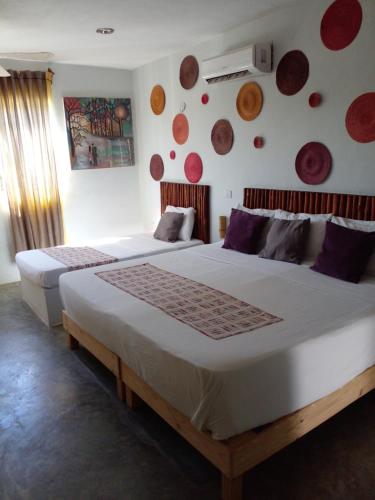 2 camas en una habitación con platos en la pared en Hotel Jardin Mahahual, en Mahahual