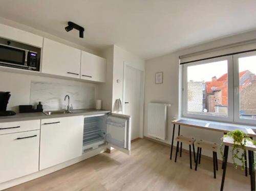 a kitchen with white cabinets and a table and a window at City and Nature in Ghent